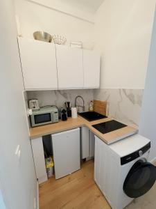 a small kitchen with white cabinets and a microwave at Quiet and bright apartment with separate bedroom in Nice +19 photos