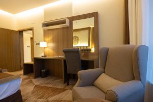 a room with a chair and a desk and a mirror at Sakura City Hotel in Al Baha