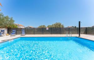 a blue swimming pool with two chairs and a fence at Stunning Home In Banj in Banj +26 photos