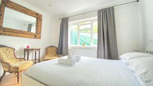 a bedroom with a white bed with a mirror and a chair at Spacious 1 Bedroom near central London Kings Cross walking to Arnos Grove Tube, Alexandra Palace, Euston in New Southgate