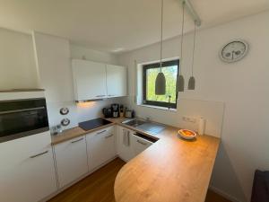 a kitchen with white cabinets and a wooden table at Apartment Henri in Schönwald