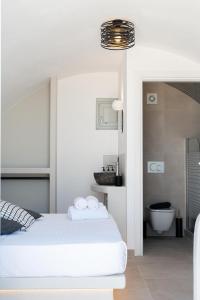 a white bedroom with a bed and a bathroom at AetherOia Suites in Oia