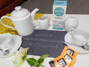 a table with a tea set and a sign that says winders chvation at Churchtown Cottage in Cubert