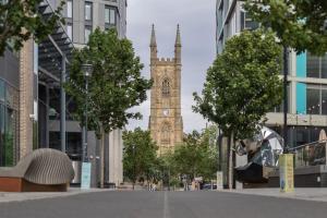 un edificio alto con una torre dell'orologio in lontananza di Unit 1 Stylish & Chic 1-BR Flat, Free Wi-Fi, Free Parking, Intimate Location a Sheffield