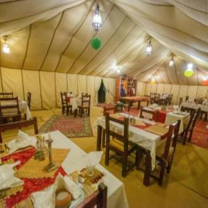 a dining room with tables and chairs in a tent at Merzouga camp in Merzouga