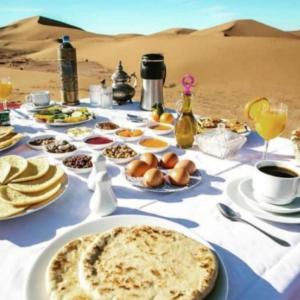 a table with food and drinks in the desert at Merzouga camp in Merzouga +27 photos