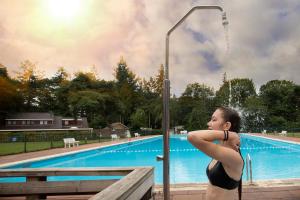 a woman standing in front of a swimming pool at Bosboerderij de Goudsberg met hottub in tuin in Lunteren