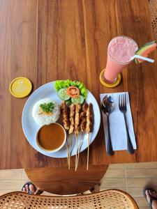 a plate of food with meat and rice and a drink at Air ilir grand villa in Gitgit