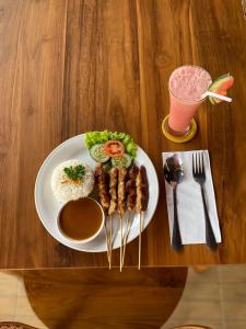 a plate of food with meat and rice and a drink at Air ilir grand villa in Gitgit