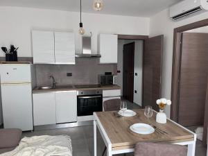 a kitchen with white cabinets and a wooden table at Domus Aura Apartments in SantʼAntìoco