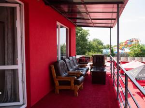 two chairs sitting on a porch with a red wall at AMSTERDAM hotel&swimming pool in Suprunovka