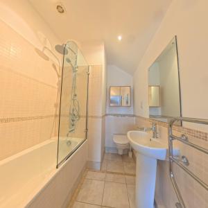 a bathroom with a sink and a shower and a toilet at Tate Five Penthouse apartment with panoramic views of St Ives in St Ives +8 photos
