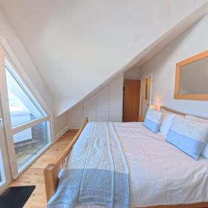 a bedroom with a large white bed with blue pillows at Tate Five Penthouse apartment with panoramic views of St Ives in St Ives