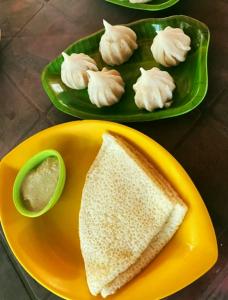 um prato amarelo com um sanduíche e um prato de bolinhos em Samant Beach Resort em Malvan