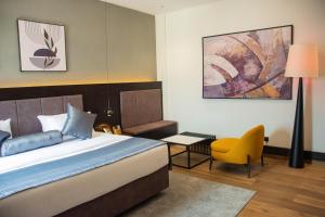 a bedroom with a bed and a yellow chair at The Thribeka International Hotel Asaba in Asaba