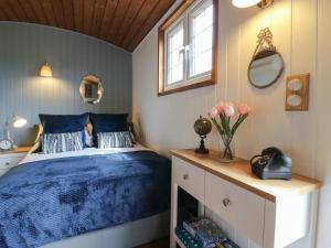una camera da letto con un letto con lenzuola blu e una finestra di Luxury Shepherd Hut with Private Hot Tub a Swaffham Bulbeck
