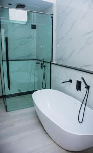 a white bath tub in a bathroom with a glass shower at The Thribeka International Hotel Asaba in Asaba +20 photos
