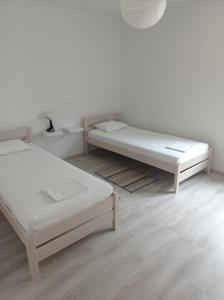 2 Betten in einem Zimmer mit weißen Wänden und Holzböden in der Unterkunft Apartmani Japa in Vrsi