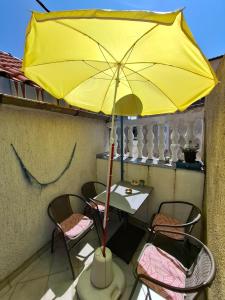 a table and chairs with a yellow umbrella on a balcony at Aretha apartman i sobe in Novi Vinodolski