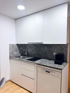 a kitchen with white cabinets and a sink at Sa Boadella - Fenals Beach in Lloret de Mar