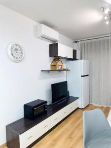 a living room with a television and a clock on the wall at Sa Boadella - Fenals Beach in Lloret de Mar
