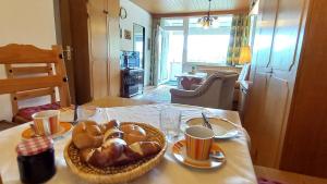 une table avec un panier de pain et des tasses dessus dans l'établissement RENATE Haus KMB Seeappartement am Ossiacher See, Hallenbad, Skiarena Gerlitzen, à Bodensdorf