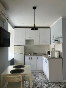 a kitchen with white cabinets and a table with chairs at Sisters apartment Val in Chernihiv +7 photos