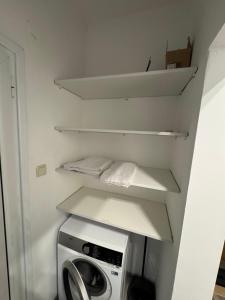 a small laundry room with a washing machine and shelves at NDK NEST 2BR Apartment in the Heart of Sofia in Sofia