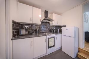 a kitchen with white cabinets and a white refrigerator at The Hampden House - Sleeps 7 in Grays Thurrock