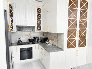 una cocina blanca con armarios blancos y horno negro en Grand House, en Bukhara