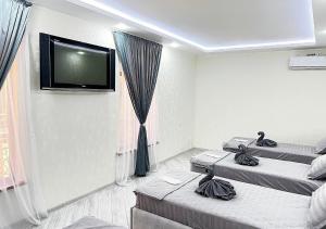 Una habitación con dos camas y un televisor de pantalla plana. en Grand House, en Bukhara