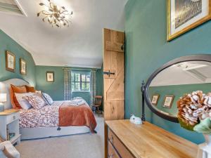 une chambre avec un lit et un miroir dans l'établissement Willow Tit Cottage, à Capel-Cynon 18 autres photos