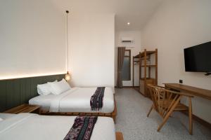 a room with two beds and a desk and a television at Green Hill Boutique Hotel in Labuan Bajo
