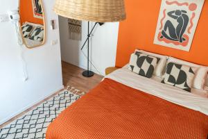 a bedroom with a bed with an orange wall at Dotan's Boutique Studios - By The Beach! in Tel Aviv