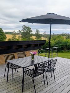 a table and chairs with an umbrella on a deck at Nordic Designer Summerhouse - With a fantastic view in Vejby