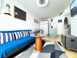 a living room with a blue couch and a table at Côté Mer - Appartement Chaleureux & Cosy - Déco Bord de Mer - Centre-Ville Rue Commerçante - Smart TV Netflix & WiFi Fibre - Cuisine Équipée & Nespresso - Check-in Autonome - Parking Facile à Proximité - Confort & Sérénité in Sens