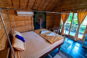 a bedroom with a bed in a room with windows at Hampi Natures Cottage in New Hampi