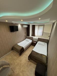 a bedroom with two beds and a flat screen tv at Grand time hotel in Yerevan +28 photos