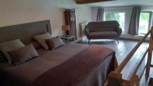 a bedroom with a bed and a couch and a chair at Sérénité in Saint-Genès-de-Castillon
