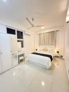 a white bedroom with a bed and a window at Urban Stays by Empress in Hulhumale