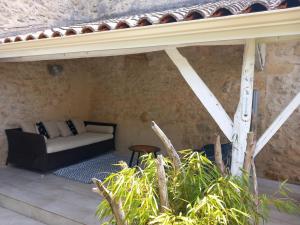 a couch sitting on a patio under a roof at Sérénité in Saint-Genès-de-Castillon