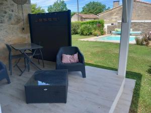 a patio with a chair and a table and a pool at Sérénité in Saint-Genès-de-Castillon
