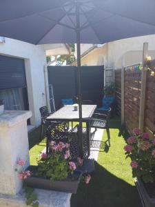 un patio con una mesa y una sombrilla en Maisonnette, en Biscarrosse