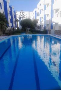 a large blue swimming pool with buildings in the background at Suit Home in Martil