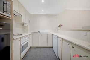 Una cocina blanca con gabinetes y electrodomésticos blancos. en MetaWise Cozy 1BR City Pad W Parking Near RPA & Sydney Uni, en Sídney