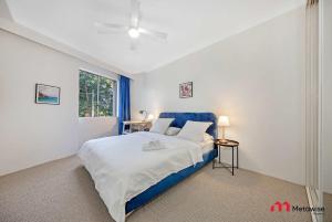 Un dormitorio con una cama azul y blanca y una ventana. en MetaWise Cozy 1BR City Pad W Parking Near RPA & Sydney Uni, en Sídney