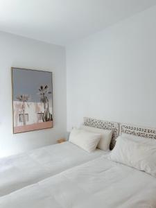 een bed met witte lakens en een schilderij aan de muur bij CalaLuna Mojácar in Mojácar +45 foto's