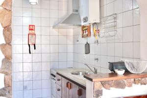 a kitchen with white tiled walls and a sink at Casa do Careca in Sagres +12 photos
