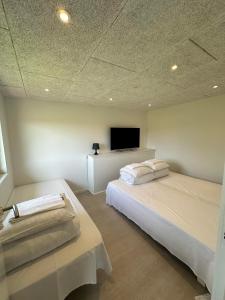 a bedroom with two beds and a flat screen tv at Fishermans House Apartment 2 in Hirtshals +21 photos