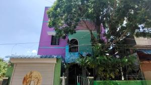 a colorful building with a tree in front of it at Param Homestay in Puducherry